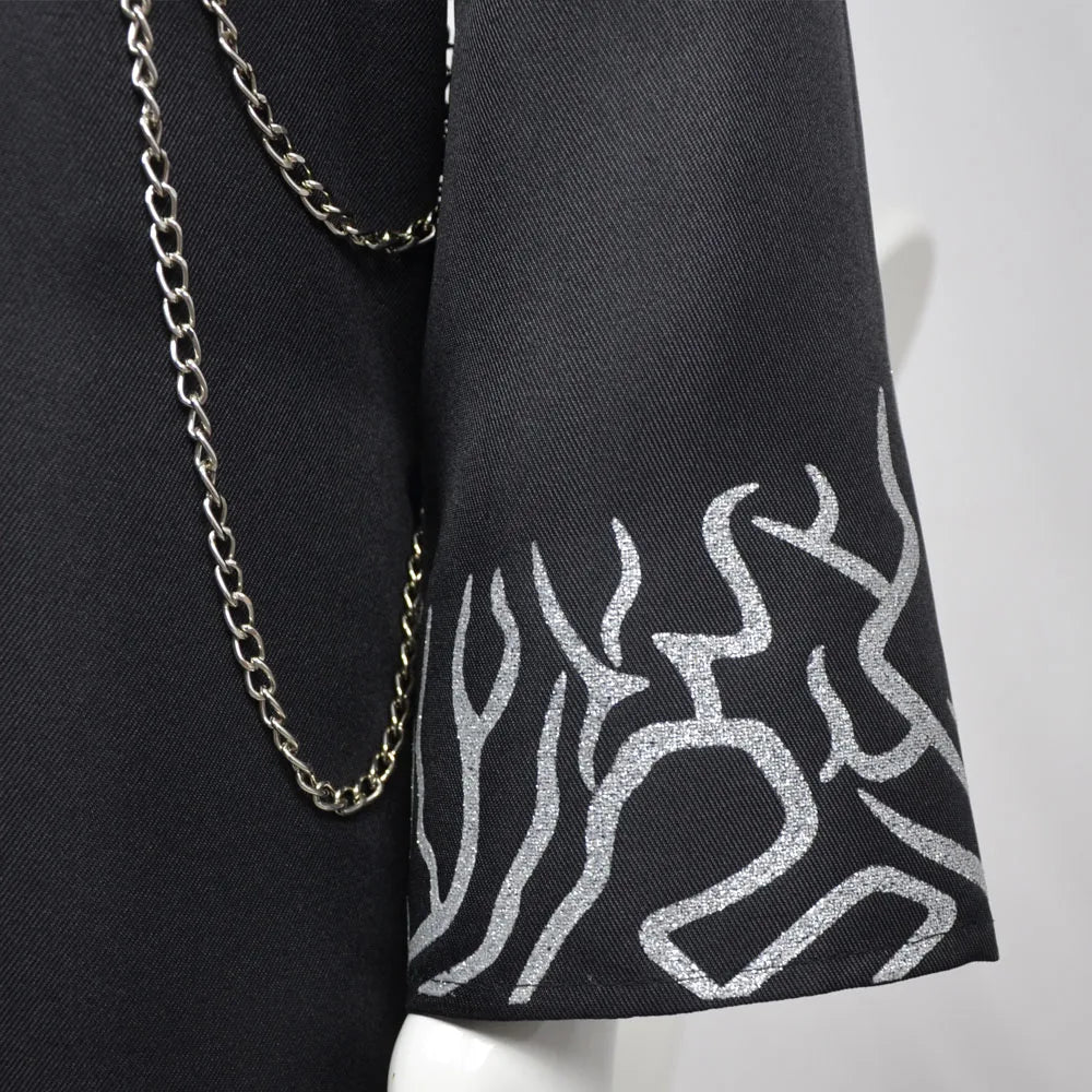 Black fabric with silver abstract pattern and gold chain on a white background
