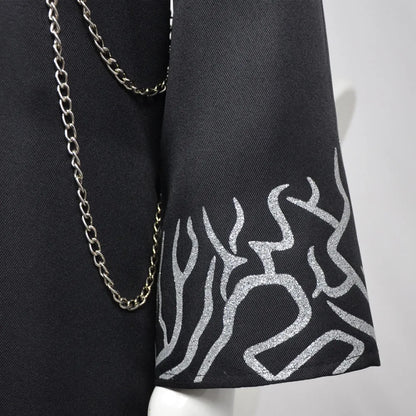 Black fabric with silver abstract pattern and gold chain on a white background
