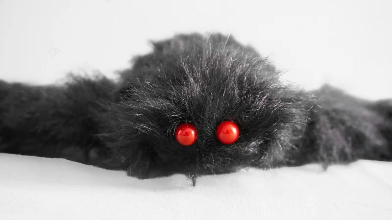 Black furry creature with red eyes on a white background