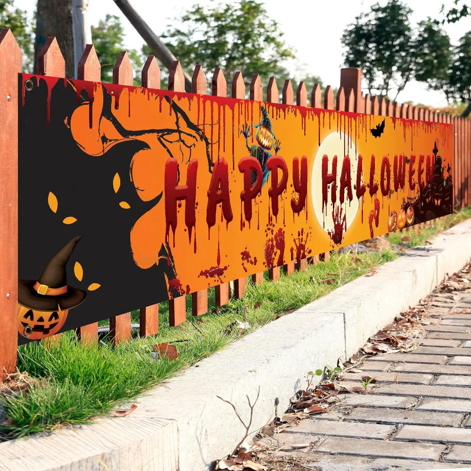 Halloween-themed decorative banner on a wooden fence with pumpkins and witches.