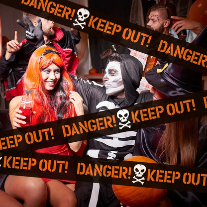 People in Halloween costumes surrounded by 'Keep Out!' tape with a skull symbol.