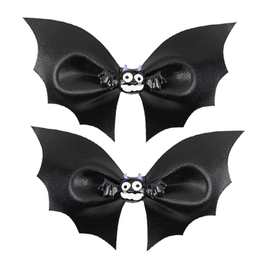 Two black bat-shaped hair bows with a small skull and crossbones center on a white background.