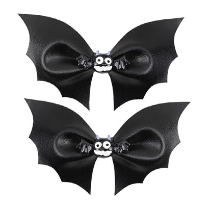 Two black bat-shaped hair bows with a small skull and crossbones center on a white background.