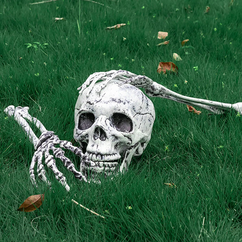 Skeletal hand reaching towards a skull on grass