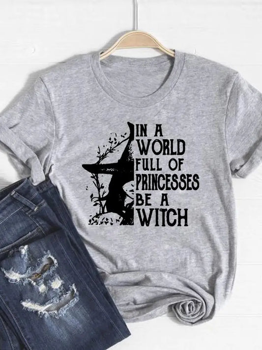 Gray t-shirt with witch graphic and text 'In a world full of princesses be a witch' on a hanger with jeans.