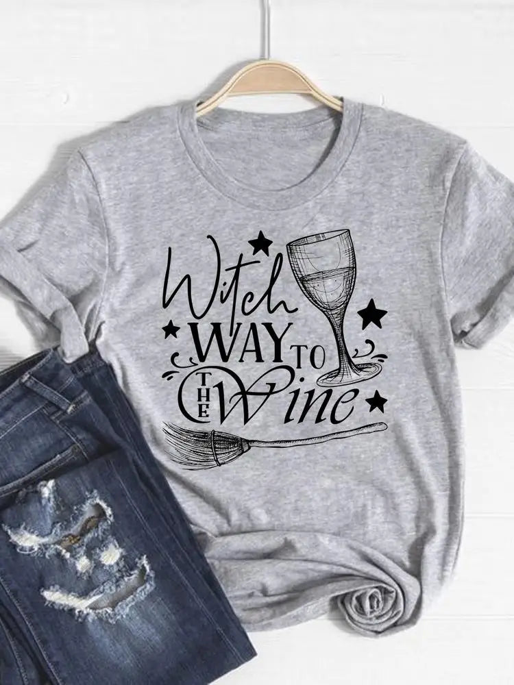 Gray t-shirt with 'Witch Way to the Wine' text and wine glass graphic on a hanger with jeans below.