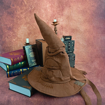 Brown wizard hat with books and a candle on a textured surface